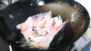 魚(yú)頭處理干凈后對(duì)半切開(kāi)，入加熱油的鍋中略煎。