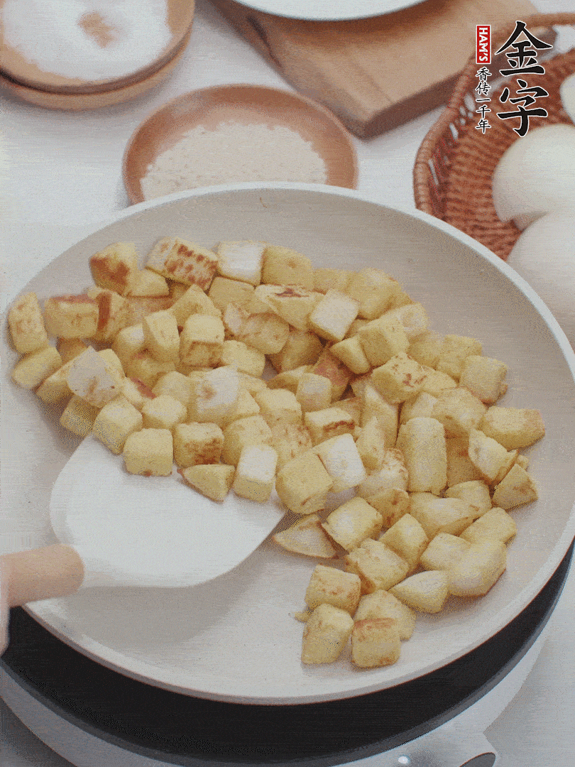 起鍋熱油，倒入饅頭丁，小火煎至蛋液凝固定型再翻面，饅頭丁部煎至金黃時(shí)盛起待用。
